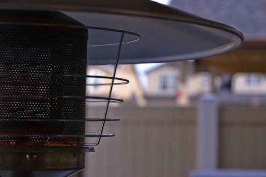 Detailed view of a modern outdoor patio heater with blurred suburban background, perfect for outdoor comfort concepts.