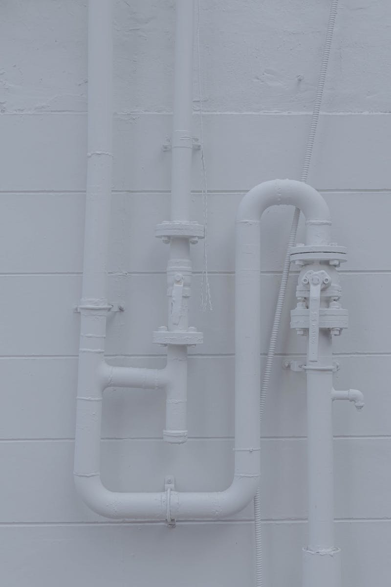 Close-up of white industrial pipes on a wall, showcasing minimalistic design.